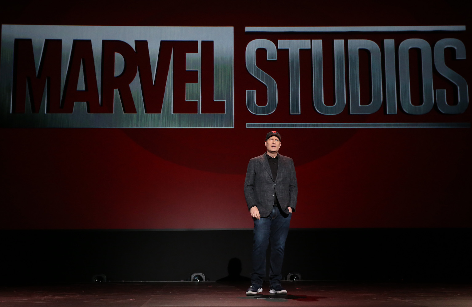 Kevin Feige at a convention, standing in front of a Marvel Studios logo