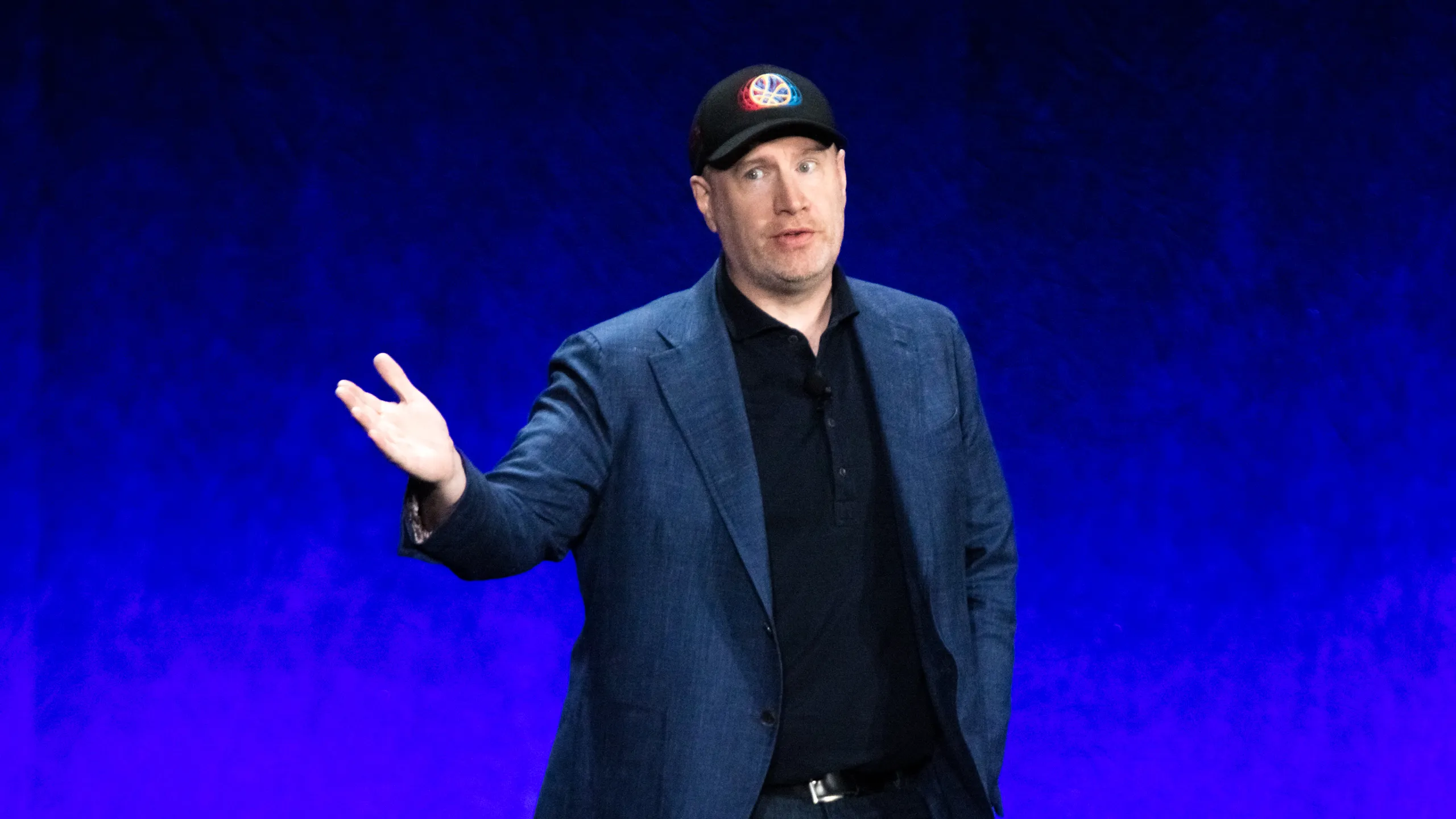 Kevin Feige standing with his arm out and a smile on his face